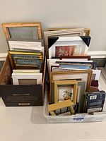 Two containers holding assorted picture frames of various sizes and colors