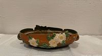 Side view of Roseville White Rose brown bowl showing floral decoration and large rim chip