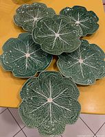 Six green cabbage-leaf plates arranged on table
