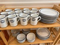 Shelved dinnerware showing mugs, dinner plates, bowls, salad plates