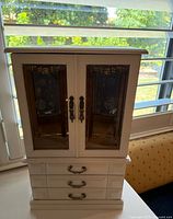 Front view showing closed glass doors and four drawers