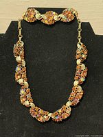 Full view of necklace displayed on black background showing design and clasp