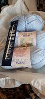 Group view of three Bernat Baby yarn balls and packaged crochet hook