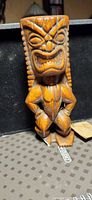 Front view of carved wooden Tiki god figurine showing overall design and damage to foot