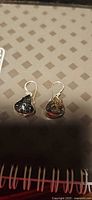 Pair of sterling silver moldavite earrings on patterned surface