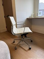 Side view of cream ribbed office chair showing chrome frame, armrest, swivel base, casters