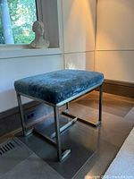 Side view of stool showing teal velvet seat and brass-tone frame