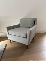Front angled view of chair showing upholstery, cushions, legs