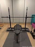 Bench, barbell on stands over floor mat