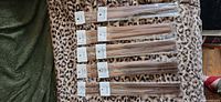 Seven clear packs of brown stick incense laid out on leopard print fabric