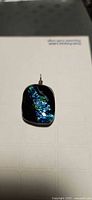 Front view of dichroic glass pendant showing iridescent blue-green pattern and sterling bail