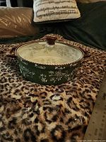 Side view of covered casserole showing green exterior floral lace design, handles, lid in place