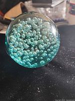 Side view of aqua-tinted leaded crystal sphere showing internal bubbles