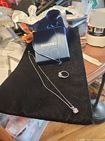 Ring, pendant necklace and Diamonelle box displayed on black fabric