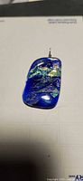 Front view of rectangular dichroic glass pendant with iridescent surface and wire bail