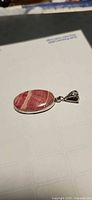 Front view of oval rhodochrosite pendant showing stone pattern and silver bail