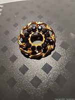 Front view of circular gold-tone brooch with garnet stones