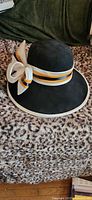 Front view of black felt hat showing brim, ribbon band and bow
