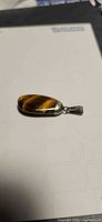 Front view of tiger eye pendant on paper background