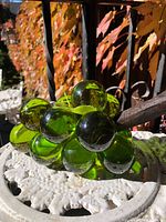 Full view of green lucite grape cluster on white surface outdoors
