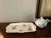 Sugar bowl with lid beside matching sandwich tray