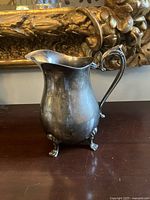 Front view of silver-plated pitcher showing lion feet and curved profile