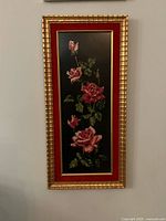 Full view of framed needlepoint showing frame, mat, and stitched rose design