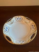 Top view of porcelain bowl showing blue bird motifs, gold scrollwork and two handles