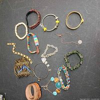 All 14 assorted bracelets laid out on black surface