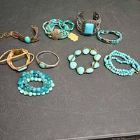 Group shot of all nine turquoise-themed bracelets laid out on black surface