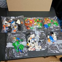 Six clear plastic bags of assorted Lego pieces on table