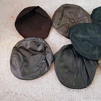 Six assorted flat caps leather, suede, tweed on carpet