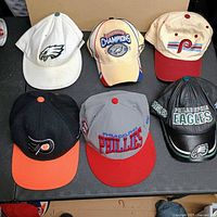 All six Philadelphia team hats displayed on table