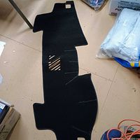 Unfolded black dash cover showing shape and cut-outs