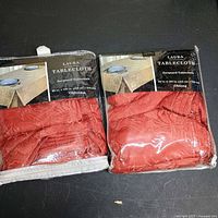 Two packaged Laura Jacquard tablecloths side by side