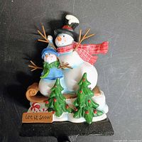 Front view of snowman stocking holder showing figures and hook
