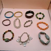 Group shot showing all 11 bracelets arranged on pink background