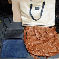 Four bags laid out: beige canvas tote, brown faux-leather tote, black wristlet pouch, blue pouch
