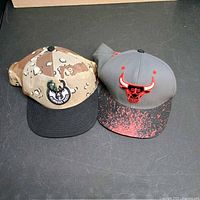 Front view of both NBA snapback hats showing team logos and brim styles