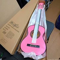 Full view of pink 30" junior classical guitar inside open box