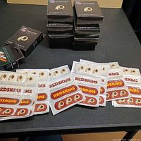 Front view of several opened packets and stacked sealed boxes showing Redskins logo and NFL branding