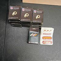 Stack of Redskins bandage boxes with one package of unfolded bandages showing team logo