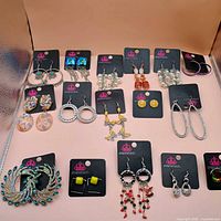 Overview of all 15 pairs of Paparazzi earrings laid out on board and surrounding area
