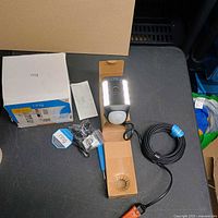 Complete contents on tabletop: Ring Spotlight Cam Wired, accessories, power cable, manuals, box