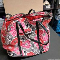 Front and side view of quilted floral tote showing pattern, handles, trim