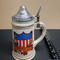 Front view of cream ceramic stein with US crest and pewter lid