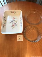 Three bakeware pieces on table: floral ceramic dish and two glass pie plates