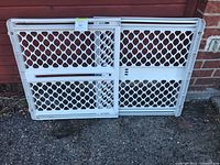 Front view of white plastic adjustable dog gate folded