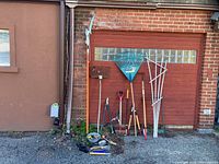 Full lot leaning against brick wall showing all long-handled tools and stakes