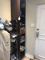 Full height view of brown tower shelf beside door